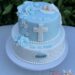 Tauftorte - Kreuz mit Zuckerperlen und süßem Baby unter der weißen Decke, ebenso auf der Torte sind blaue Rosen.