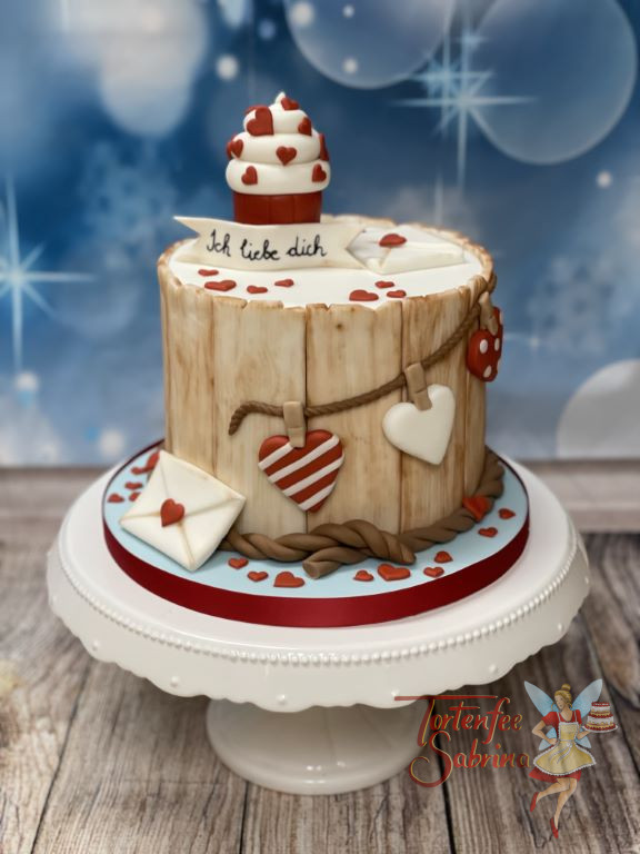 Anlasstorte - Cupcake mit Herzchen ziert ganz oben die Torte, seitlich wurde sie mit Herzen und Briefen dekoriert.