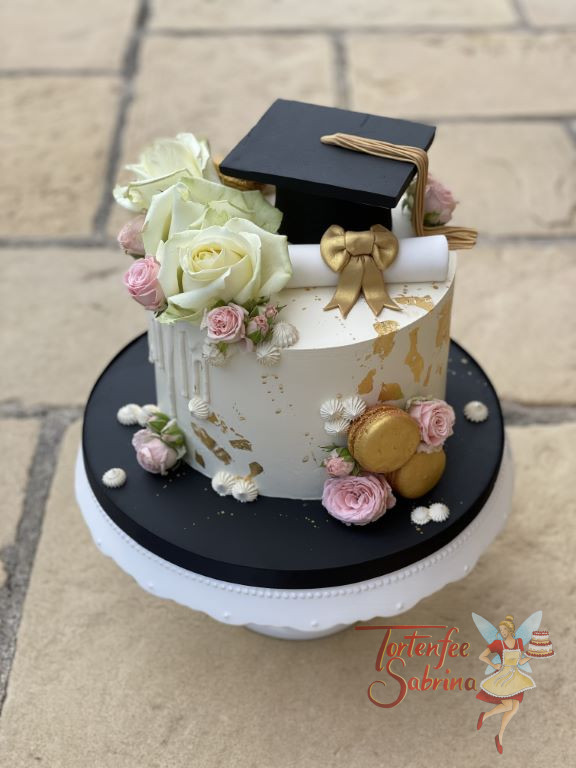 Anlasstorte - Diplom mit Rosen in zwei Farben und Blattgold mit goldenen Macarons. Oben auf der Torte ist der berühmte Diplomhut.