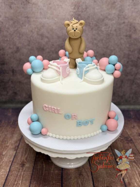Babytorte - Ein rosa Schuh und ein blauer Schuh verzieren neben dem Teddybär und vielen Kugeln die Überraschung.