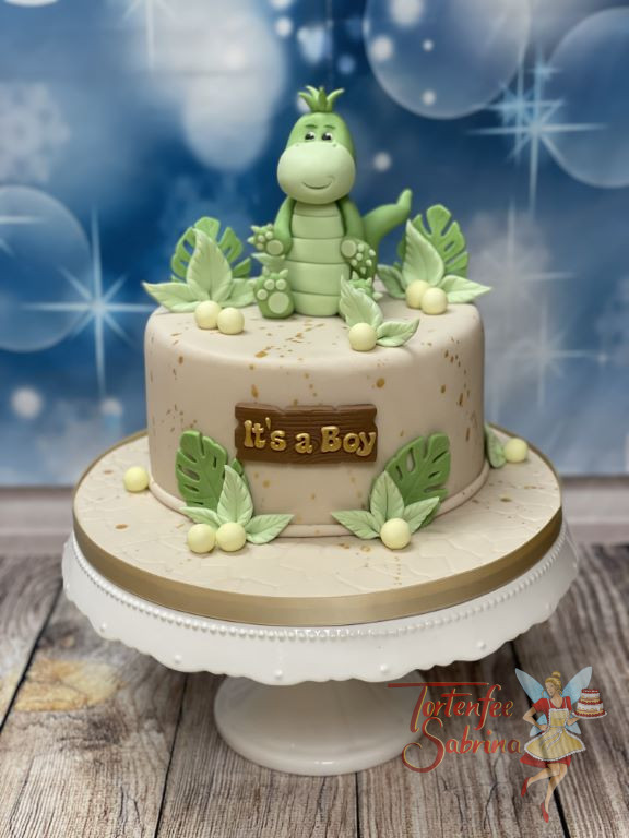 Babytorte - Kleines grünes Dinobaby sitzt oben auf der Torte, umgeben von vielen grünen Blättern und einem Holzschild.