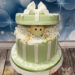 Babytorte - Kleines Wunder in Form eines Baby schaut aus der grün gestreiften Schachtel heraus und freut sich.