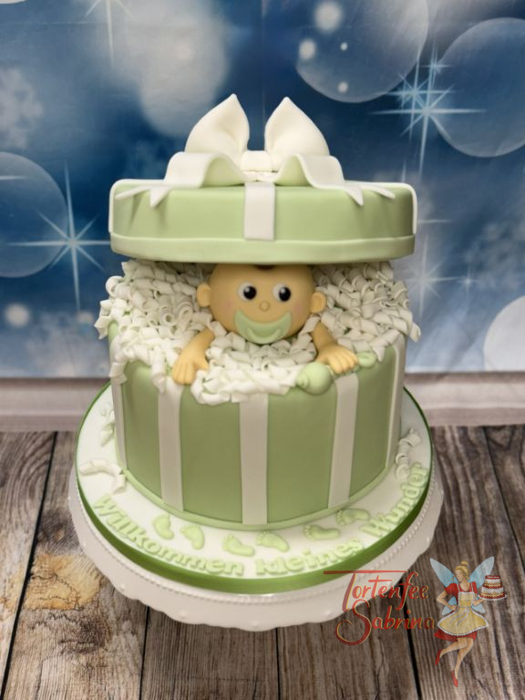 Babytorte - Kleines Wunder in Form eines Baby schaut aus der grün gestreiften Schachtel heraus und freut sich.