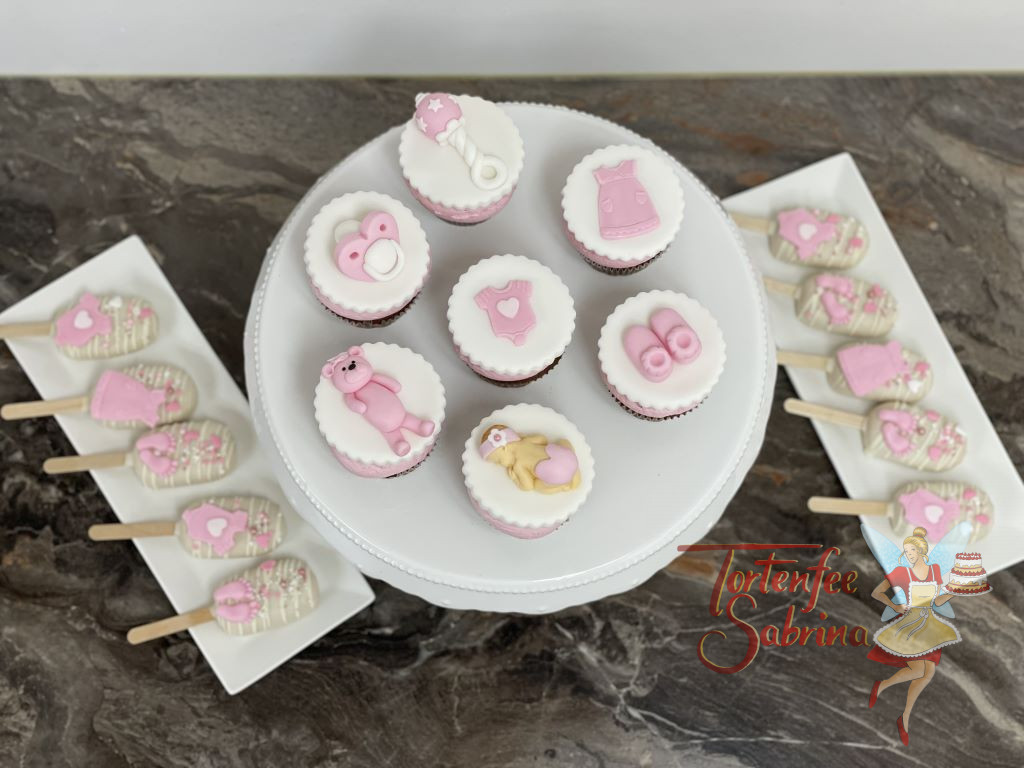 Cupcakes und Cakesicles - Rosa Babysachen, wie ein Kleid, Teddybär, Schnuller und Babyschüchen zieren diese wunderbaren Süßigkeiten.