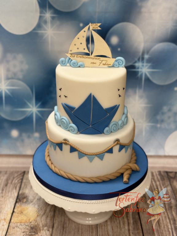 Erstkommunionstorte - Blaues Boot in den Wellen verziert den oberen Stock der Torte, ganz oben ist ein passender Caketopper.