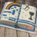 Erstkommunionstorte - Buch mit Regenbogen und anderen typischen Symbolen wie Kreuz und Kelch verzieren die Torte.