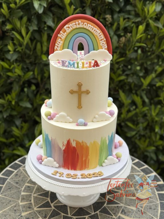Erstkommunionstorte - Bunter Regenbogen ziert ganz oben neben dem goldenen Kreuz die zweistöckige bunte Torte.