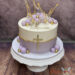 Erstkommunionstorte - Lila Kugeln und eine Zuckerschale mit goldenem Rand sind oben auf der Torte neben dem Caketopper platziert.
