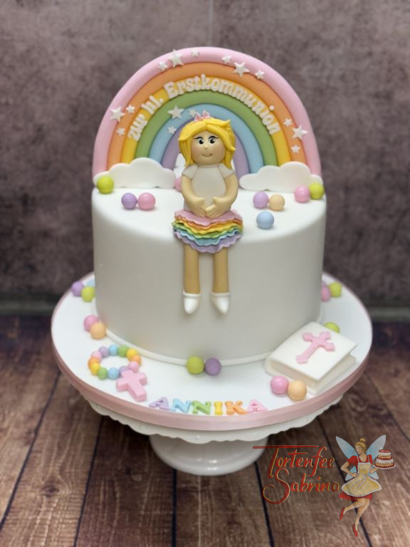 Erstkommunionstorte - Rock in Regenbogenfarben wird von einem kleinen blonden Mädchen getragen, welches vor einem Regenbogen sitzt.