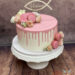 Erstkommunionstorte - Rosa Blumen und Macarons zieren den rosa Drip Cake. Ganz oben ist ein personalisierte Caketopper.