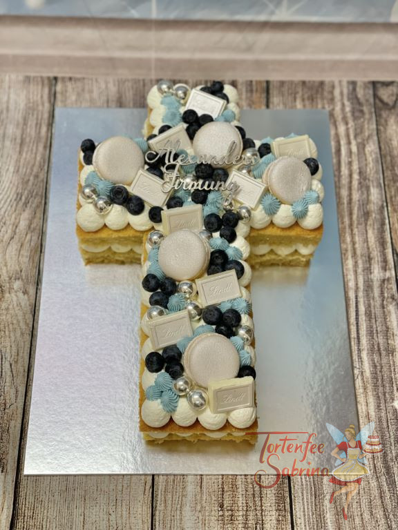 Firmungstorte - Blau-Silbernes Kreuz mit Schokolade und Macarons in silberner Farbe ist zusätlich noch mit dem passenden Caketopper verziert.
