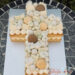 Firmungstorte - Süßes Kreuz würde hier mit Macarons, Schokolade und weißen Blumen verziert.