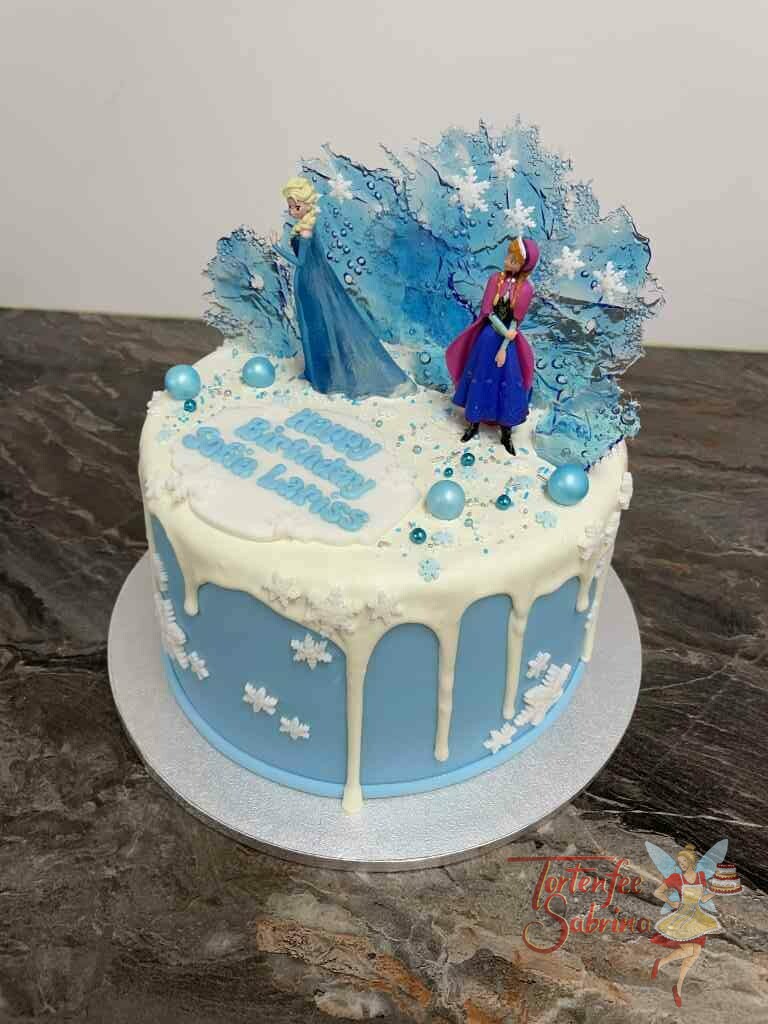 Geburtstagstorte Mädchen - Anna und Elsa in der Eiswelt sind hier auf der Torte zu sehen, ein weißer Drip ziert ebenso die Torte.