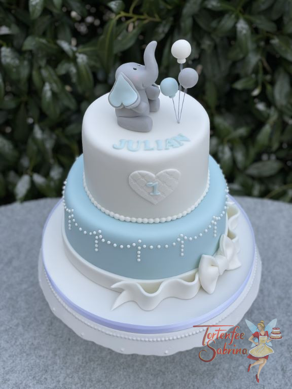 Geburtstagsorte Buben - Babyelefant mit Luftballon sitzt ganz oben auf der Torte, der untere Abschluss ist eine weiße Schleife.