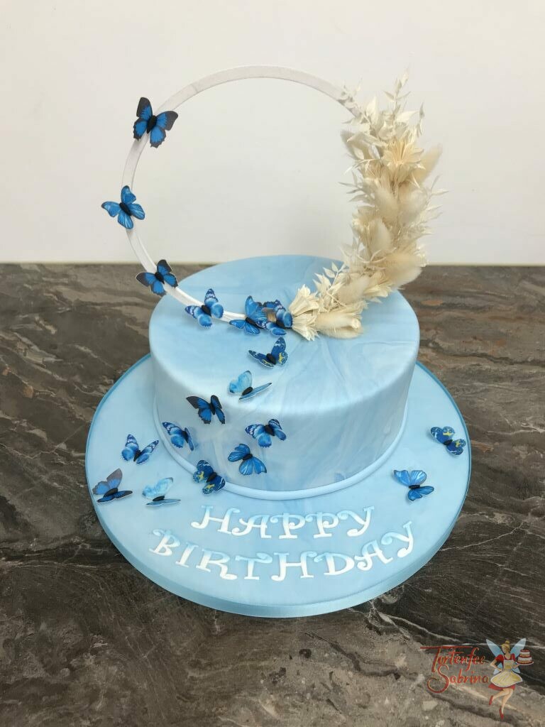 Geburtstagstorte Erwachsene - Blaue Schmetterlinge mit Trockenbumen auf weißen Ring, krönen die blau marmorierte Torte.