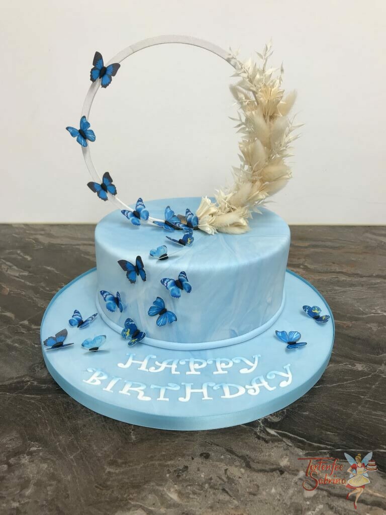 Geburtstagstorte Erwachsene - Blaue Schmetterlinge mit Trockenbumen auf weißen Ring, krönen die blau marmorierte Torte.