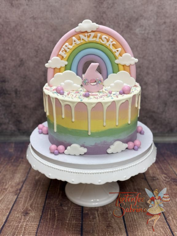 Geburtstagstorte Mädchen - Buntes Regebogenmuster verziert seitich die Torte, der Drip und der Regenbogen verschönern oben die Torte.