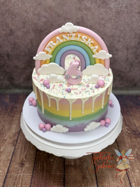Geburtstagstorte Mädchen - Buntes Regebogenmuster verziert seitich die Torte, der Drip und der Regenbogen verschönern oben die Torte.