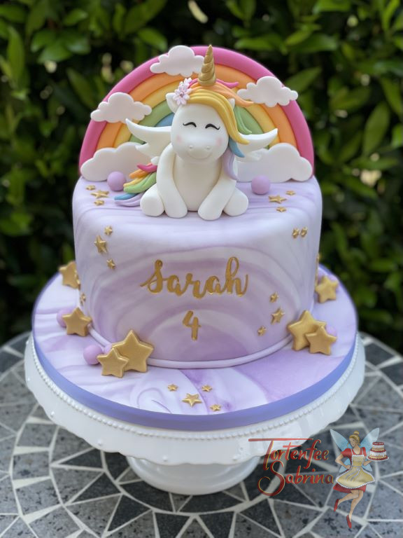 Geburtstagstorte Mädchen - Das fliegende Einhorn sitzt vor einem Regenbogen auf der im Marble-Effeckt eingedeckte Torte.