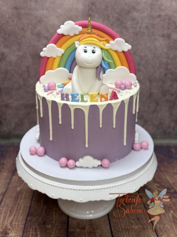 Geburtstagstorte - Das liebenswerte Einhorn sitzt vor dem bunten Regenbogen und lässt sich den Wind durch die Mähne wehen.