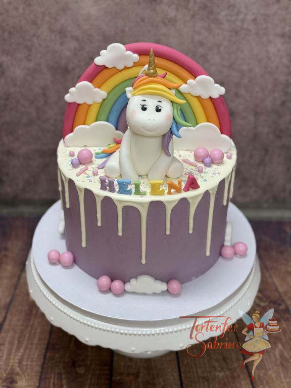 Geburtstagstorte - Das liebenswerte Einhorn sitzt vor dem bunten Regenbogen und lässt sich den Wind durch die Mähne wehen.