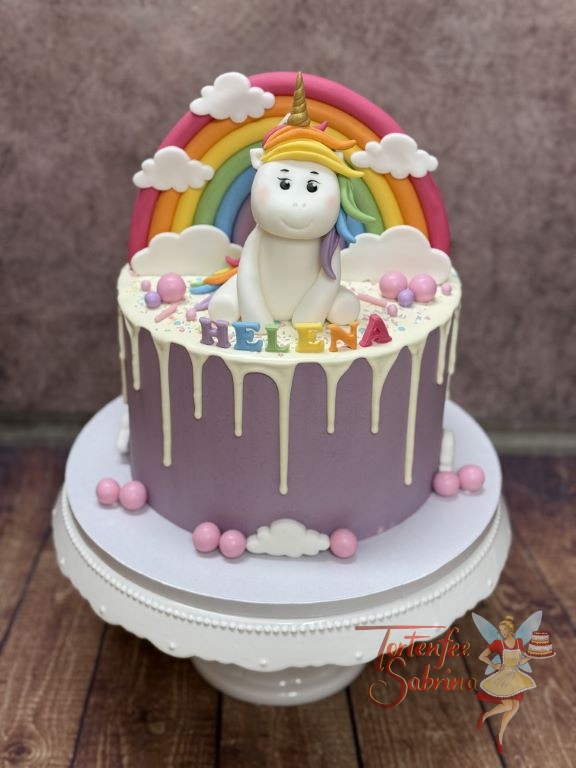 Geburtstagstorte - Das liebenswerte Einhorn sitzt vor dem bunten Regenbogen und lässt sich den Wind durch die Mähne wehen.