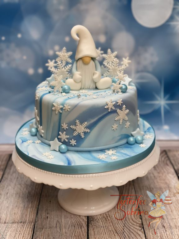 Geburtstagstorte Erwachsene - Der Eiswichtel sitzt umgeben von vielen Schneeflocken auf der Torte die mit einem Marble-Effekt eingedeckt ist.