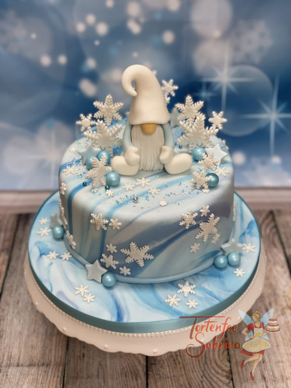 Geburtstagstorte Erwachsene - Der Eiswichtel sitzt umgeben von vielen Schneeflocken auf der Torte die mit einem Marble-Effekt eingedeckt ist.
