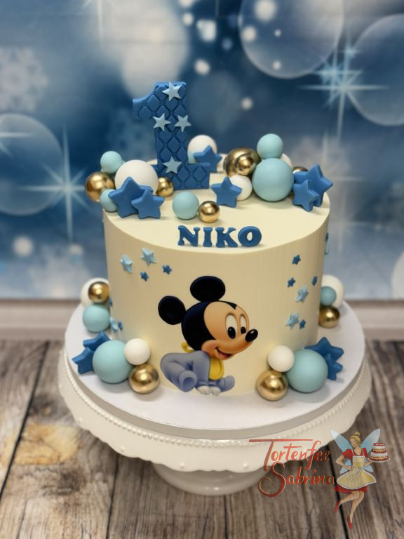 Geburtstagstorte Buben - Der kleine Baby Mickey krabbelt vor der Torte herum, ganz oben auf der Torte ist eine blaue Eins.