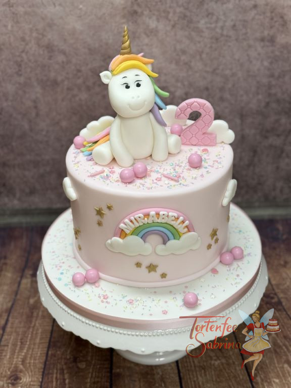 Geburtstagstorte - Der kleine Regenbogen ist vorne auf der Torte gut sichtbar und oben sitzt das lachende Einhorn.