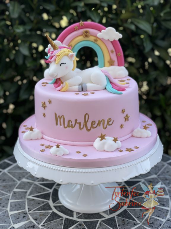 Geburtstagstorte Mädchen - Einhorn mit Sternchen liegt und macht es sich auf der Torte vor dem Regenbogen gemütlich.