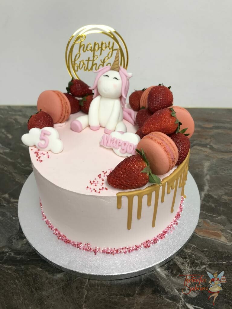 Geburtstagstorte Mädchen - Einhorn zwischen Früchten und Süßem, sitzt oben auf der Torte welche mit einem goldenem Drip und Cake Topper verziert wurde.