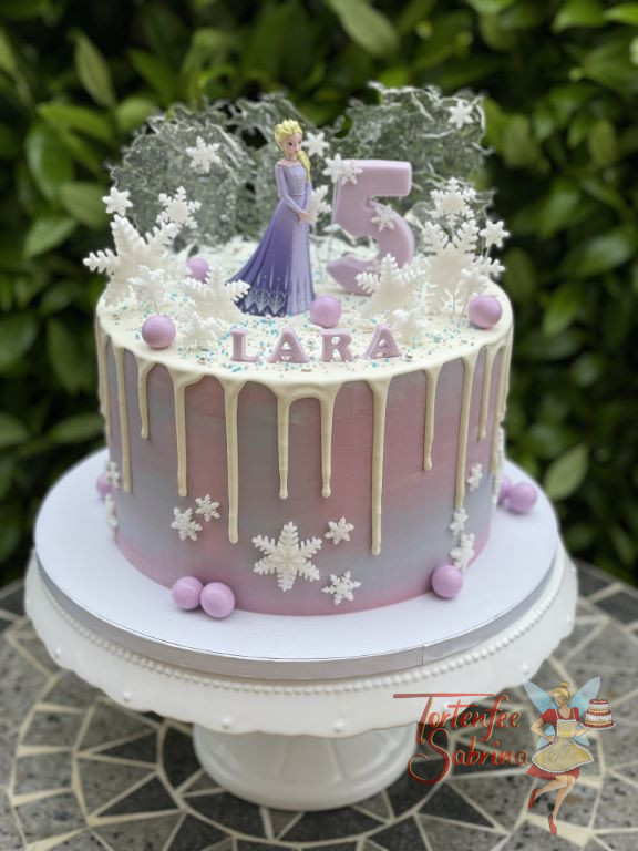 Geburtstagstorte Mädchen - Elsa in violett steht ganz oben auf dem weißen Drip Cake umgeben von Schnee und Eis.