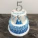 Geburtstagstorte Mädchen - Elsa mit Rüschen in unterschiedlichen Blautönen. Dekoriert mit Elsa, Schneeflocken und einem Cake Topper.
