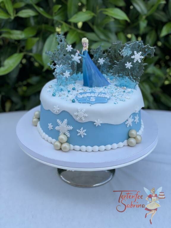 Geburtstagstorte Mädchen - Elsa und die Eiskristalle in mitten der weißen Schneedecke und Schneeflocken mit glitzernden Zuckerperlen.