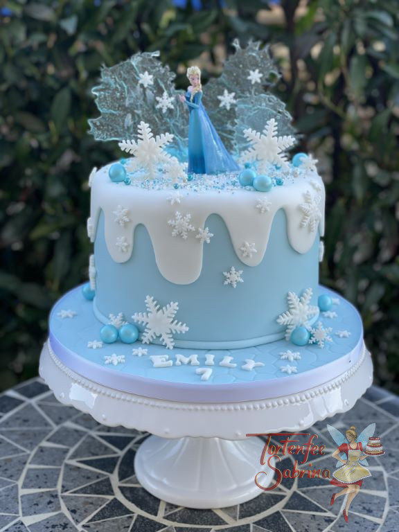 Geburtstagstorte Mädchen - Elsas ewiges Eis ist hier im Hintergrund zu sehen, rundherum ist die Torte mit Schneeflocken verziert.