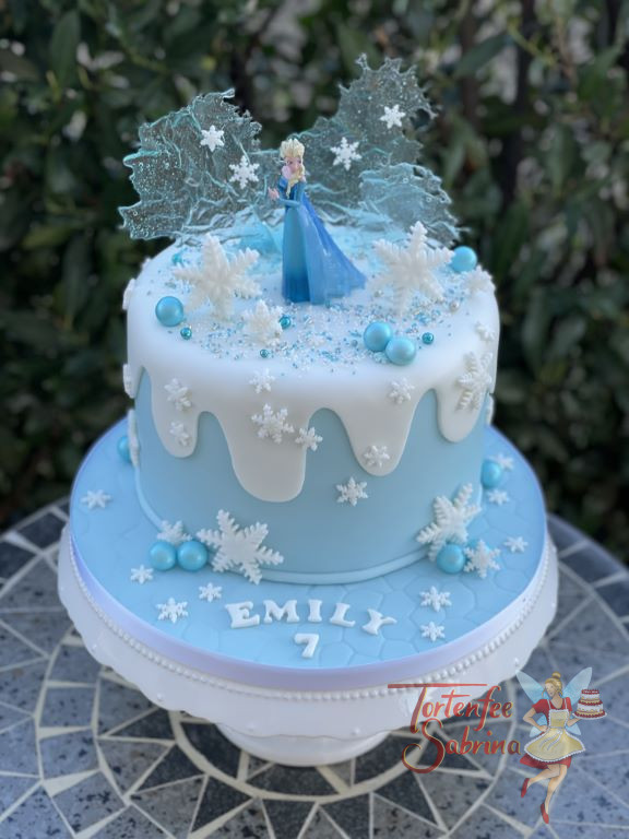Geburtstagstorte Mädchen - Elsas ewiges Eis ist hier im Hintergrund zu sehen, rundherum ist die Torte mit Schneeflocken verziert.