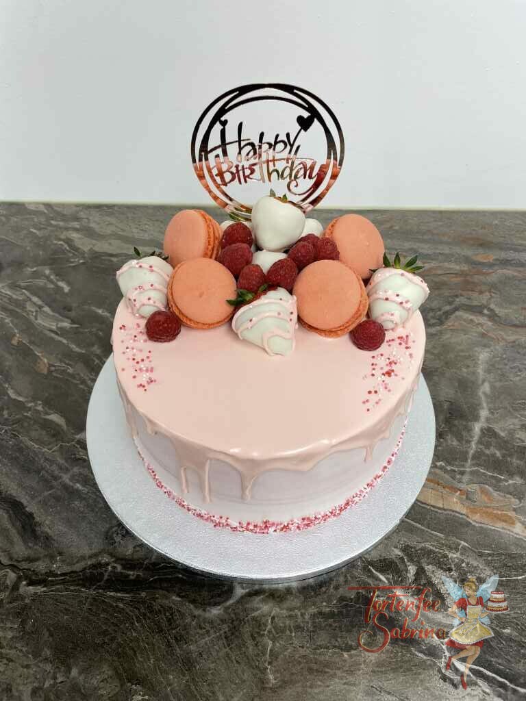 Geburtstagstorte Erwachsene - Erdbeer-Drip-Cake ist eine rosa farbene Torte mit vielen Süßigkeiten und Früchten oben drauf.