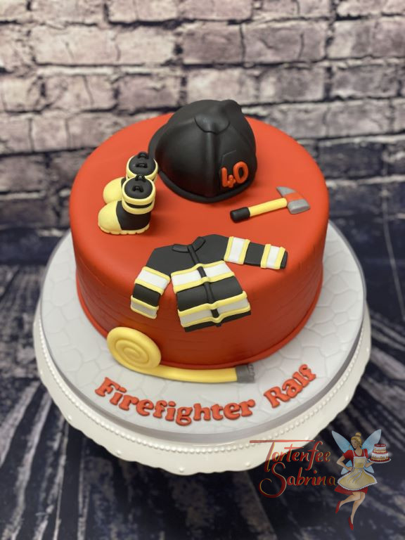 Geburtstagstorte Erwachsene - Feuerwehrstiefel, Feuerwehrjacke und Feuerwehrhelm zieren diese ganz rote Torte.