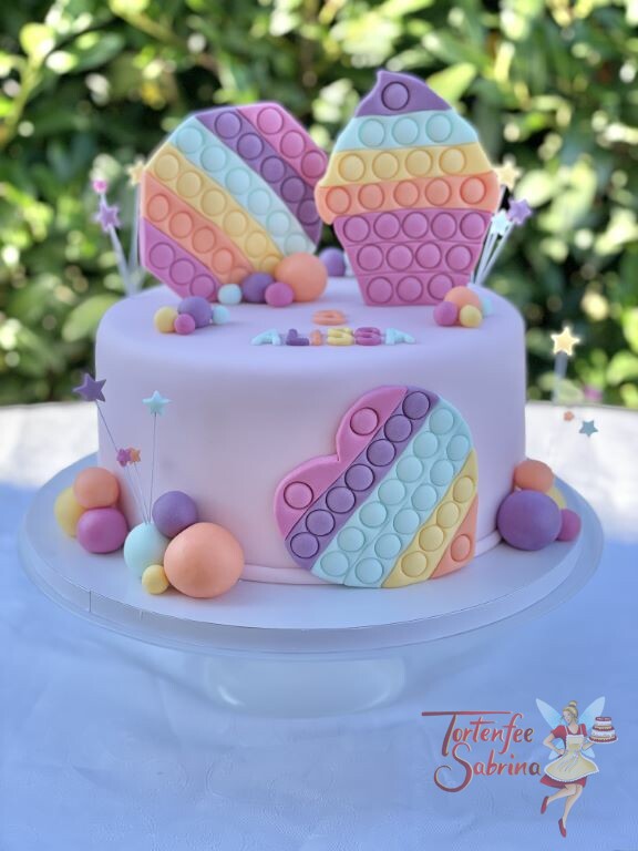Geburtstagstorte Mädchen - Figettoys in vielen Farben zieren die rosa eingedeckte Torte, ebenso auf der Torte sind bunte Sterne.
