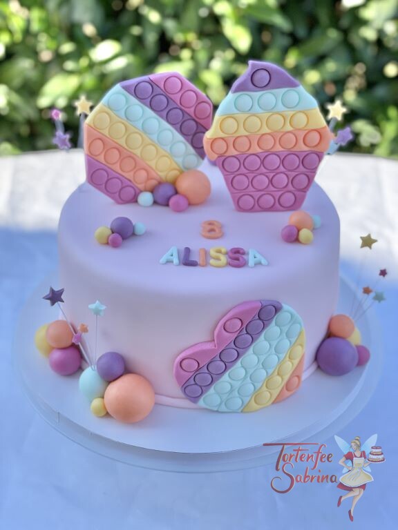 Geburtstagstorte Mädchen - Figettoys in vielen Farben zieren die rosa eingedeckte Torte, ebenso auf der Torte sind bunte Sterne.
