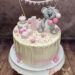 Geburtstagstorte Mädchen - Freudiger Koalabär sitzt oben auf dem Drip Cake und schaut auf seine Geschenke und die kleine Torte.