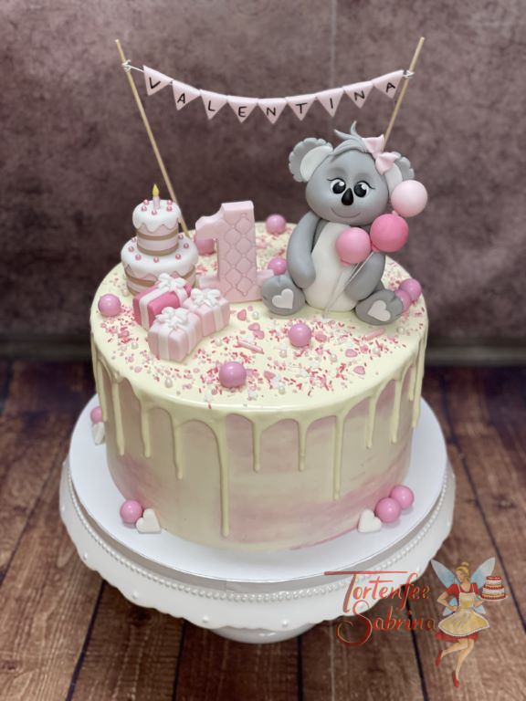 Geburtstagstorte Mädchen - Freudiger Koalabär sitzt oben auf dem Drip Cake und schaut auf seine Geschenke und die kleine Torte.
