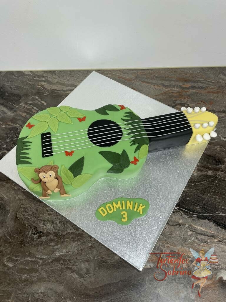 Geburtstagstorte Buben - Gitarre mit Dschungel und vielen Blättern, ebenfalls auf der Torte sitzt noch ein kleiner süßer Affe.