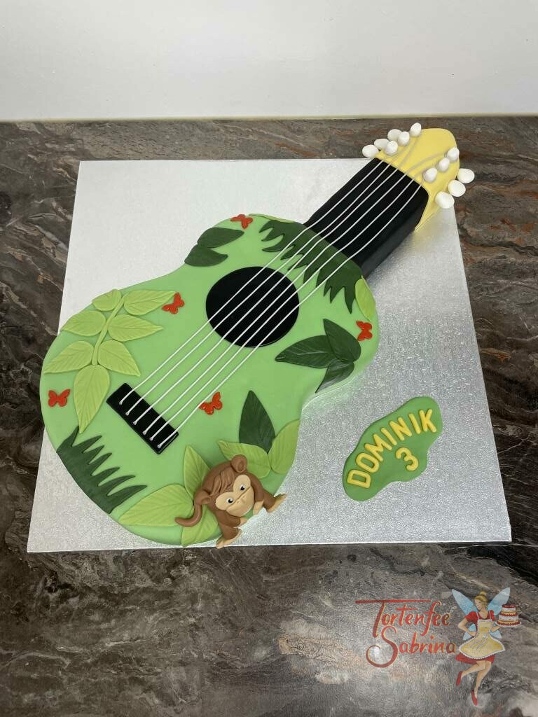 Geburtstagstorte Buben - Gitarre mit Dschungel und vielen Blättern, ebenfalls auf der Torte sitzt noch ein kleiner süßer Affe.