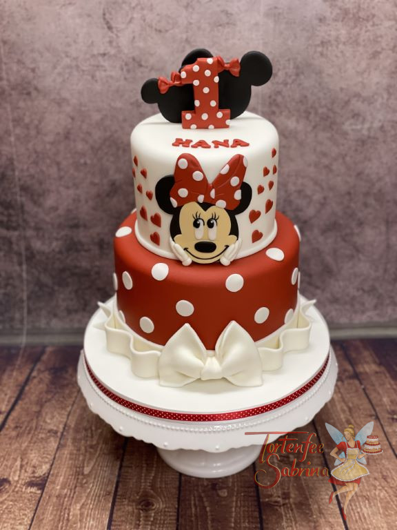 Geburtstagstorte Mädchen - Glückliche Minnie Mouse lacht von der Torte, das zweistöckige Werk wurde mit Herzen und Schleifen verziert.