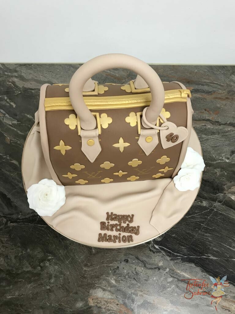 Geburtstagstorte Erwachsene - Gold-braune Tasche als Torte mit dem typischem goldenen Muster und Buchstaben, ebenso sind weiße Rosen neben der Tasche.