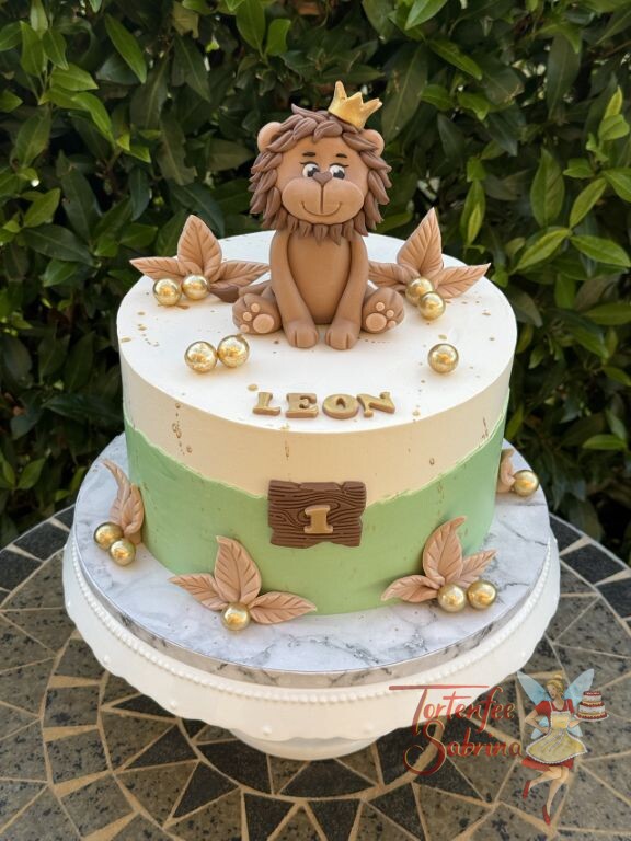 Geburtstagstorte Buben - Goldiger Löwe mit Krone sitzt ganz oben auf der Torte umgeben von kleinen Blättern und Kugeln.