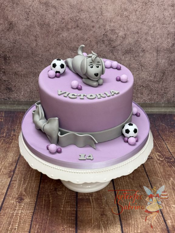 Geburtstagstorte Mädchen - Graues Hündchen liegt vergnügt auf der lila Torte und bewundert die schöne graue Schleife.