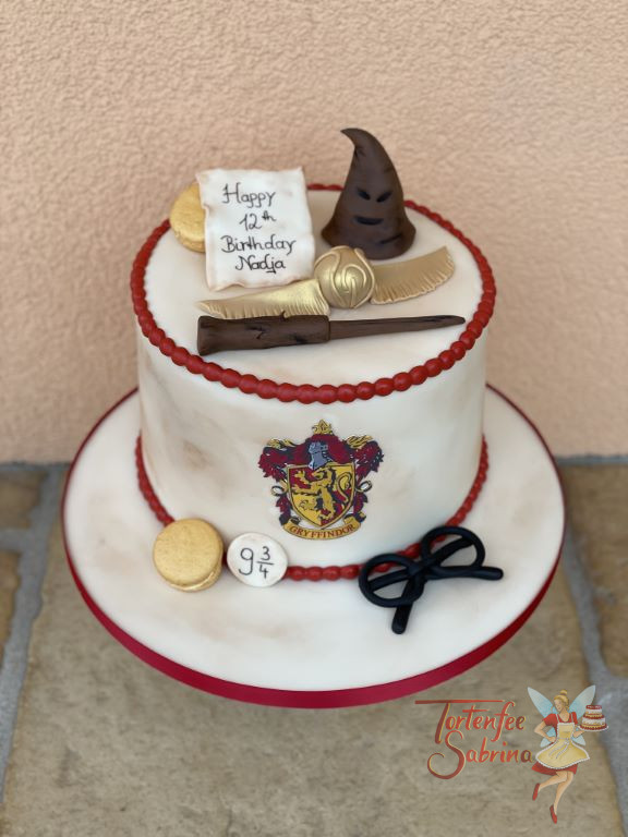 Geburtstagstorte Mädchen - Hogwarts Gryffindor Wappen ziert vorne die Torte, oben drauf liegt der goldene Schnatz.